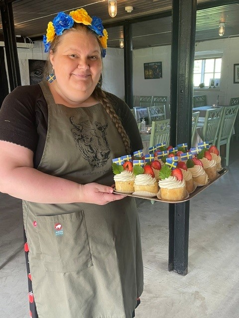 Maria står i cafeéet med nationaldagsbakelser på en bricka
