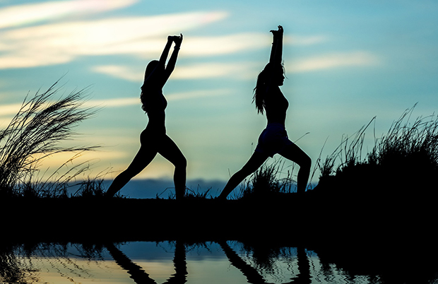 Yogande siluetter vid vatten